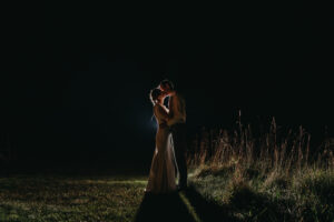 Bride and groom kissing at night backlit